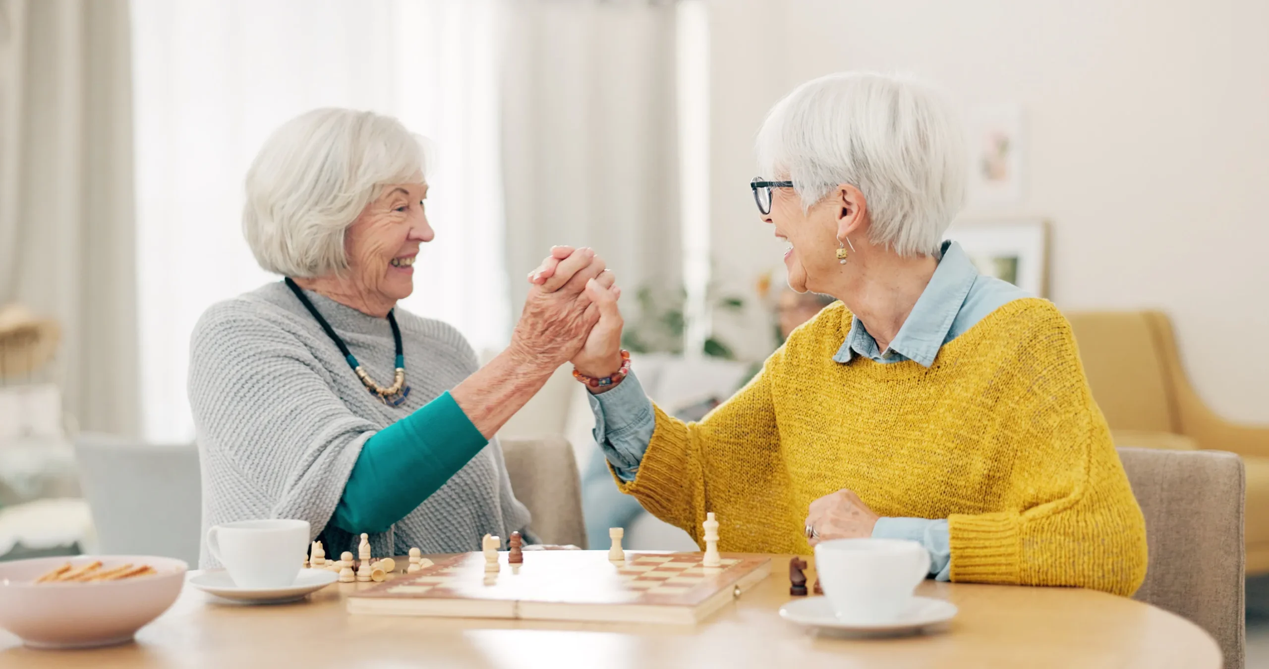 Senior woman, friends and high five for chess match, game or winning on table together at home